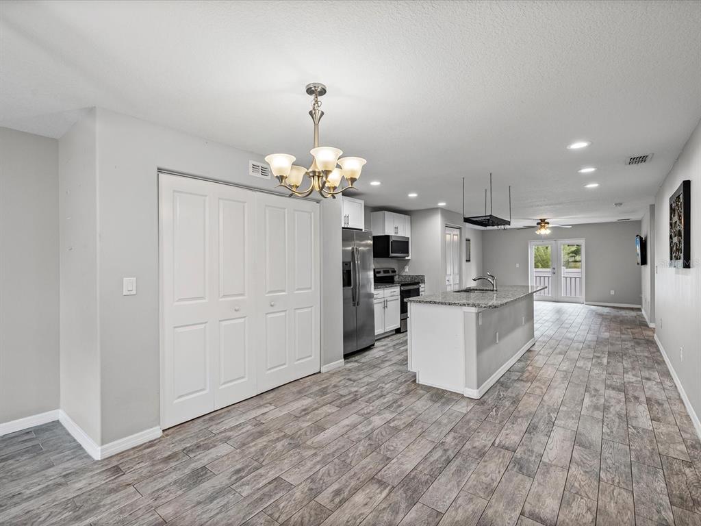 1238 Vista Way Clearwater, FL 33755 - Photo 6 of 32 a large kitchen with kitchen island a stove a refrigerator a sink dishwasher with a dining table and chairs with wooden floor