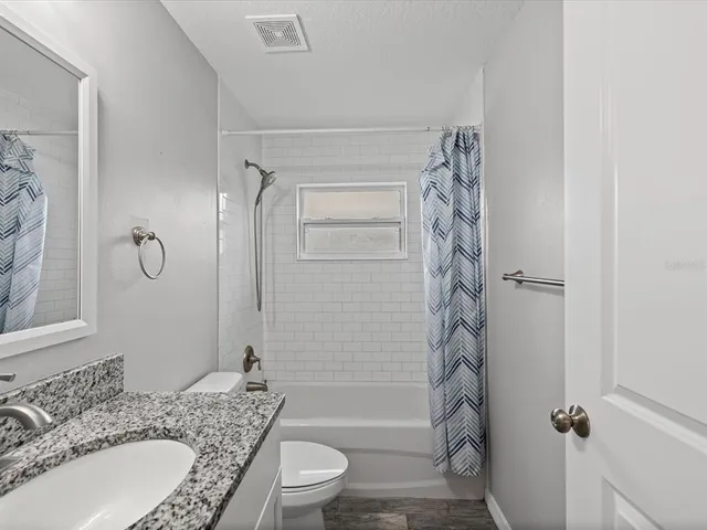 a bathroom with a granite countertop sink toilet and shower