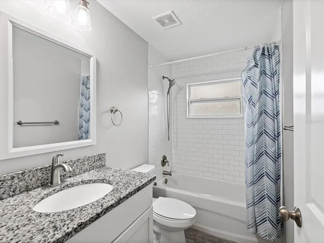 a bathroom with a granite countertop sink toilet a mirror and shower