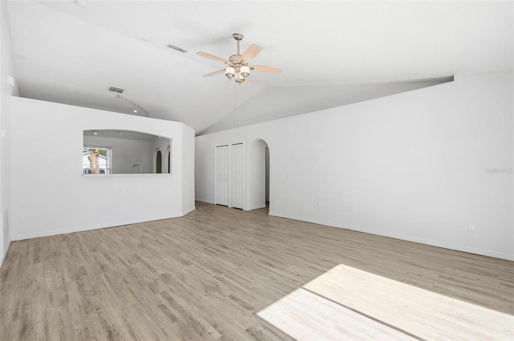 80 Providence Lane Palm Coast, FL 32164 - Photo 16 of 42 a view of an empty room with wooden floor and a ceiling fan