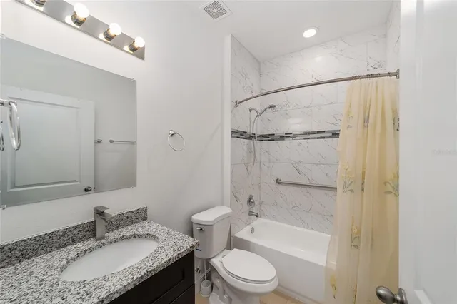 a bathroom with a granite countertop sink toilet and shower