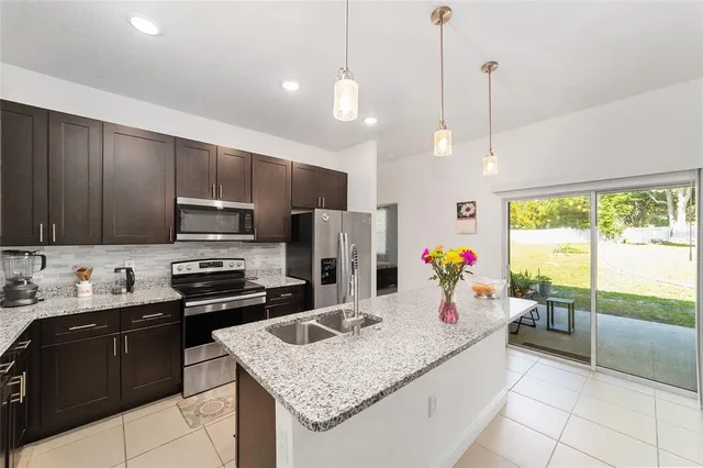 a kitchen with a stove a sink a refrigerator and chairs