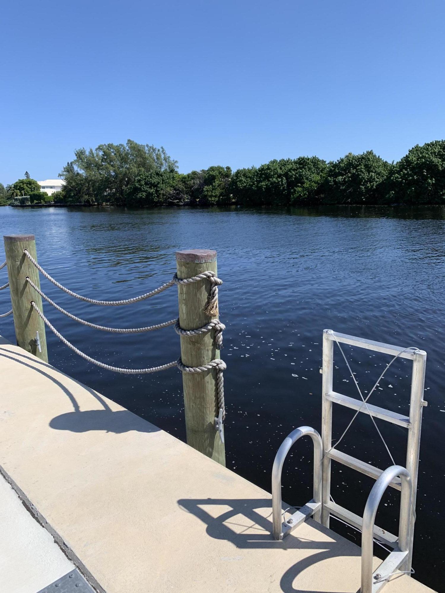 19 Colonial Club Drive, Unit 202 Boynton Beach, FL 33435 - Photo 14 of 18 a wooden bench sitting next to a lake