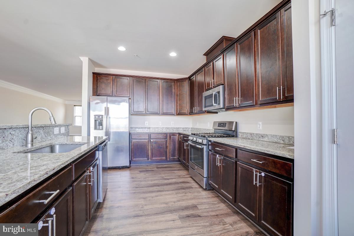 1709 Fieldstone Court Hanover, MD 21076 - Photo 14 of 30 a kitchen with stainless steel appliances granite countertop wooden cabinets sink stove and refrigerator