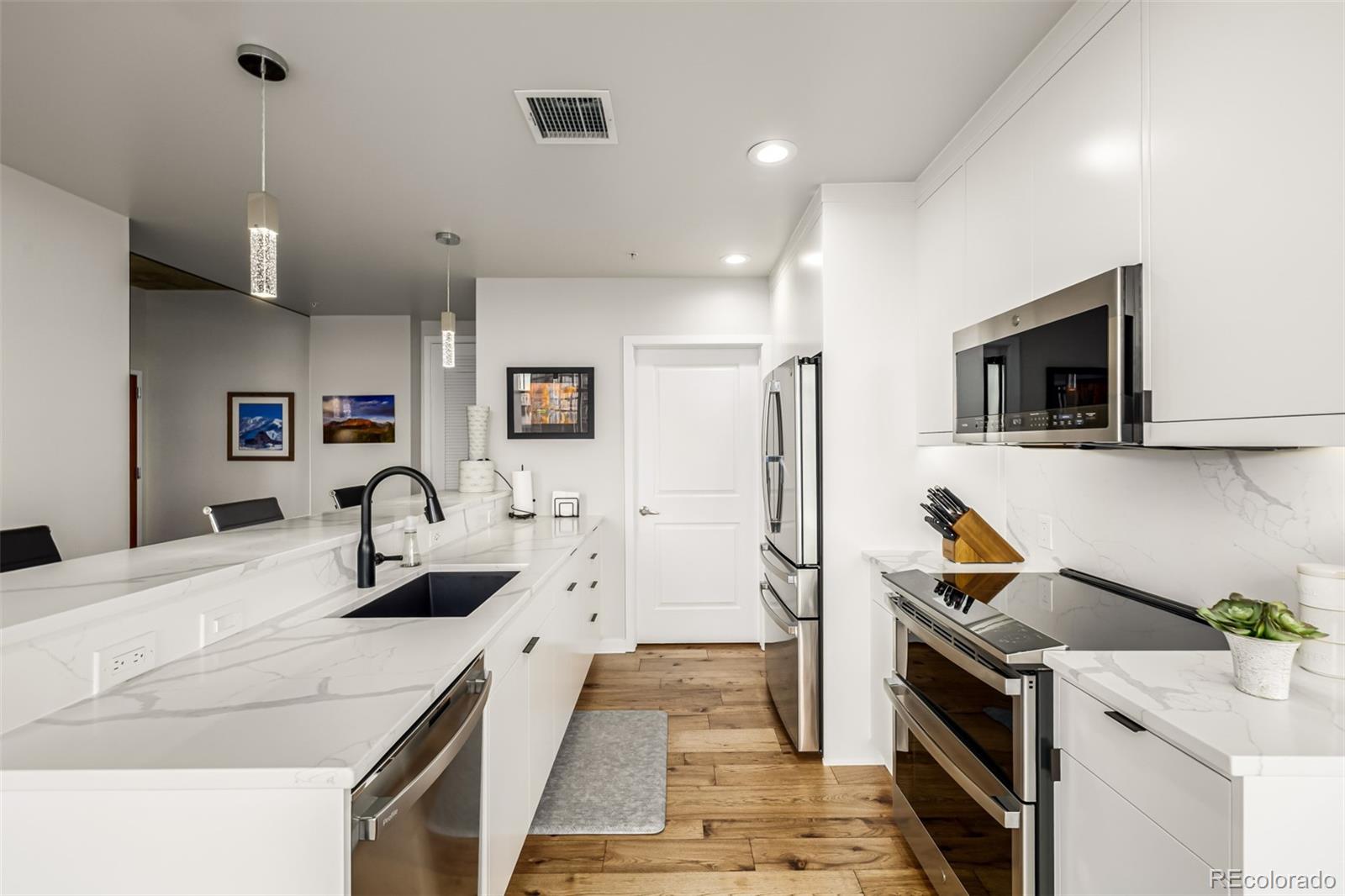 1700 Bassett Street, Unit 1412 Denver, CO 80202 - Photo 4 of 43 a kitchen with stainless steel appliances kitchen island granite countertop a sink and refrigerator