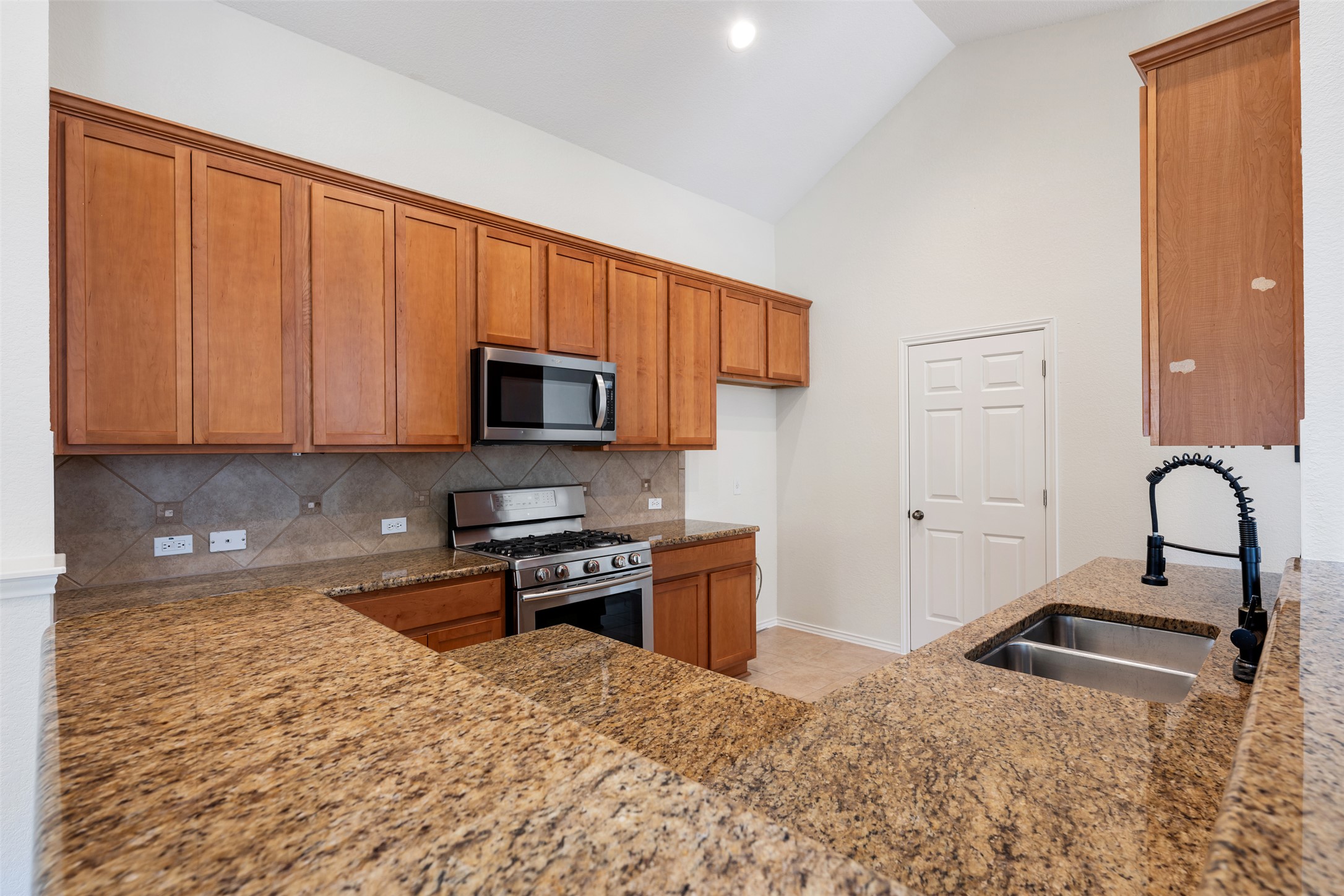 14316 Marathon Road Austin, TX 78717 - Photo 26 of 40 Vaulted ceilings and warm granite countertops define this functional kitchen workspace.