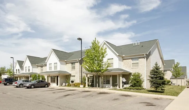 a front view of a building with lot of cars and trees