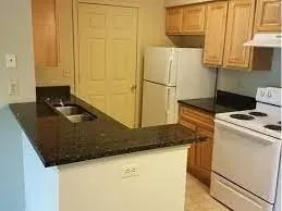 a kitchen with granite countertop a sink a stove and a refrigerator