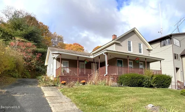 a front view of a house with a garden and trees