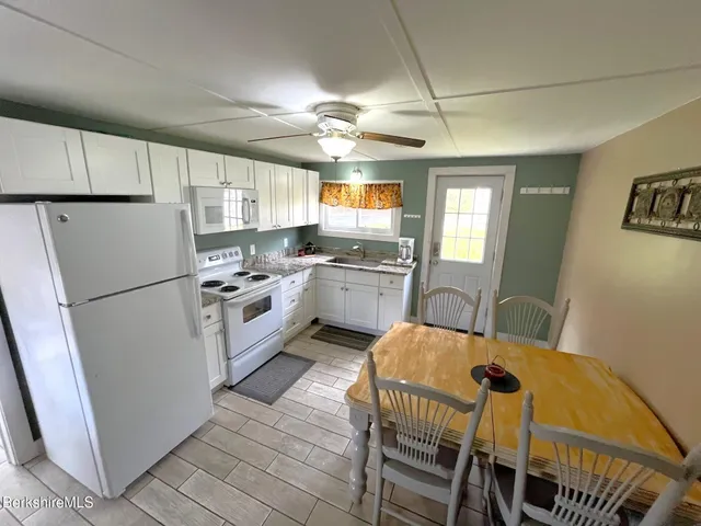 a kitchen with a refrigerator a stove a sink dishwasher a dining table and chairs with wooden floor