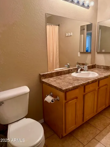 a bathroom with a granite countertop toilet sink and mirror