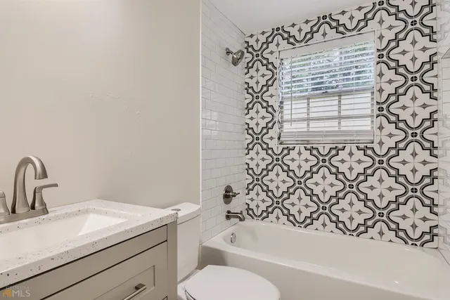 a bathroom with a granite countertop sink toilet and bathtub