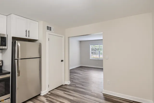 a view of a kitchen with refrigerator and wooden floor