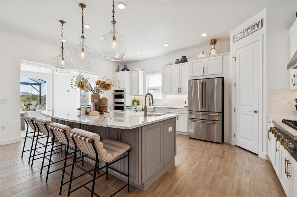 4848 Rosatti Road Wesley Chapel, FL 33543 - Photo 26 of 90 a kitchen with stainless steel appliances kitchen island a refrigerator a stove a sink and a dining table with wooden floor