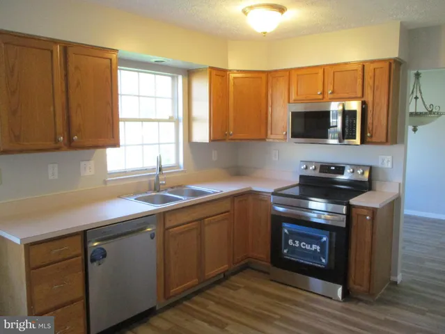 a kitchen with stainless steel appliances granite countertop a sink a stove a microwave cabinets and a window