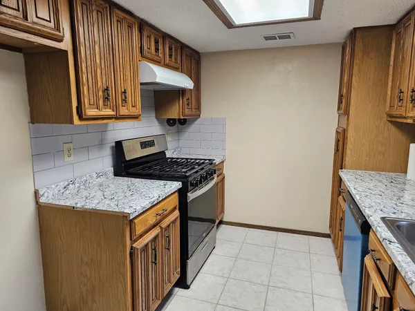 a kitchen with granite countertop cabinets stainless steel appliances and a counter space