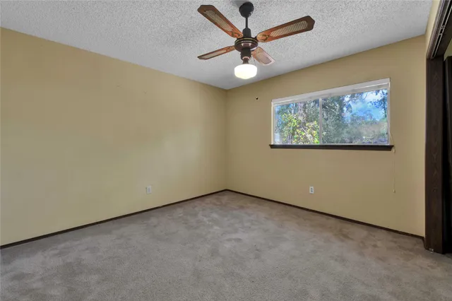 an empty room with a fan & a ceiling fan