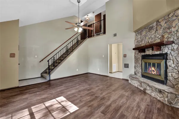 a view of an empty room with wooden floor a fireplace and a window