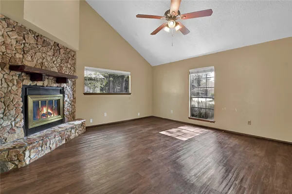 a view of an empty room with wooden floor fireplace and a window