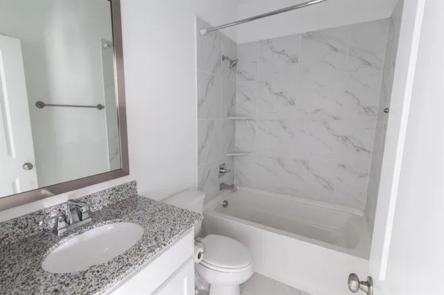 a bathroom with a granite countertop sink toilet and shower