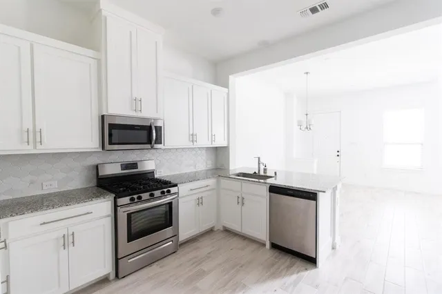 a kitchen with granite countertop white cabinets and white appliances