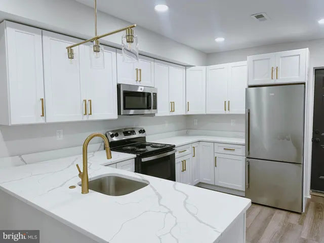 a kitchen with a refrigerator sink and white cabinets