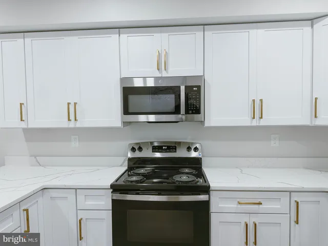 a kitchen with stainless steel appliances white cabinets and a stove top oven