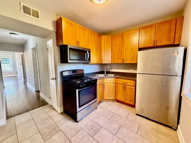 a kitchen with granite countertop a refrigerator and a stove top oven