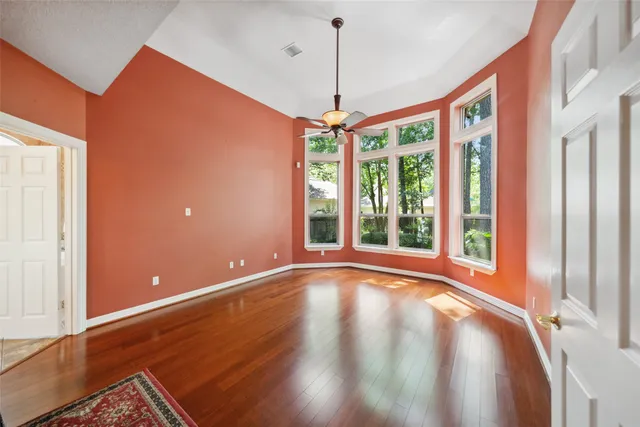 a view of an empty room with a window and wooden floor