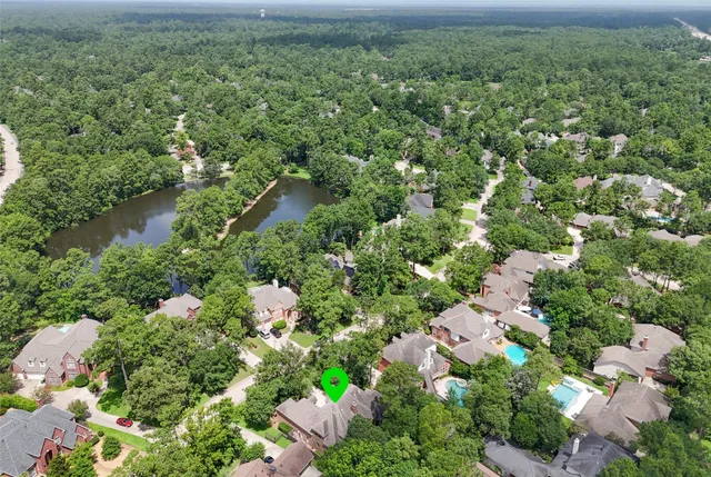 an aerial view of residential house with outdoor space and trees all around