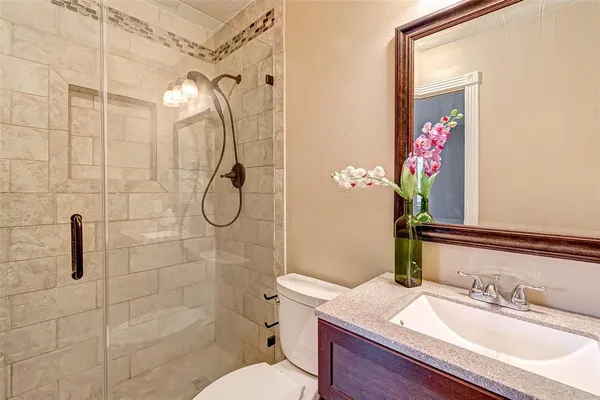 a bathroom with a granite countertop sink a toilet and shower