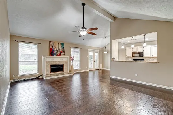 a view of an empty room with a kitchen and wooden floor