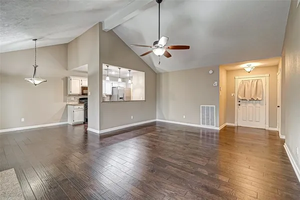 a view of an empty room with wooden floor and a ceiling fan