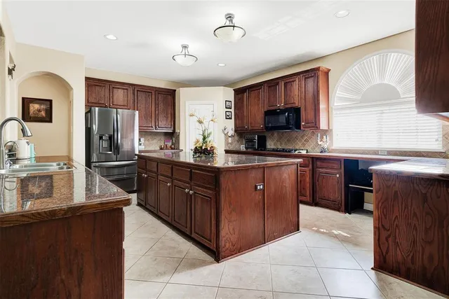 a kitchen with stainless steel appliances granite countertop a refrigerator and a stove top oven