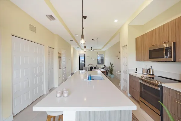 a large white kitchen with kitchen island a large counter top space a sink stainless steel appliances and cabinets
