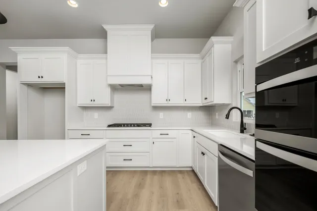a kitchen with white cabinets stainless steel appliances and sink