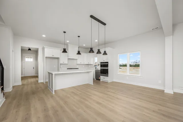 a large white kitchen with kitchen island a sink stainless steel appliances and cabinets