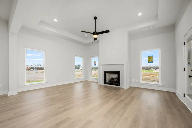 a view of an empty room with wooden floor fireplace and a window