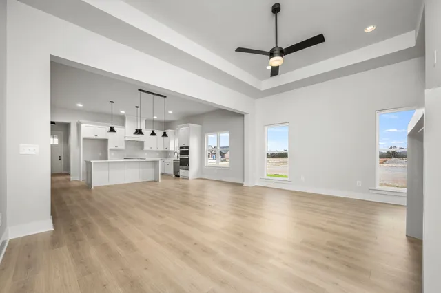 a view of an empty room with window and wooden floor