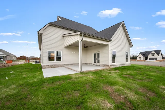 a view of a white house in front of a big yard with large trees