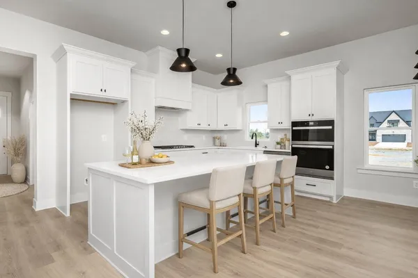 a kitchen with stainless steel appliances granite countertop a stove top oven a refrigerator a sink and a dining table with wooden floor