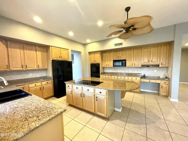 a kitchen with stainless steel appliances kitchen island granite countertop a stove refrigerator and cabinets