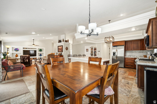 1985 West Rivers Edge Lane St. George, UT 84770 - Photo 17 of 42 Dining area featuring vaulted ceiling, a ceiling fan, suspended lighting, built in shelves, and light stone finish floors