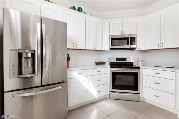 a kitchen with stainless steel appliances white cabinets white stove a refrigerator and a microwave