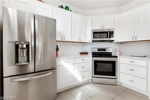 a kitchen with stainless steel appliances white cabinets white stove a refrigerator and a microwave
