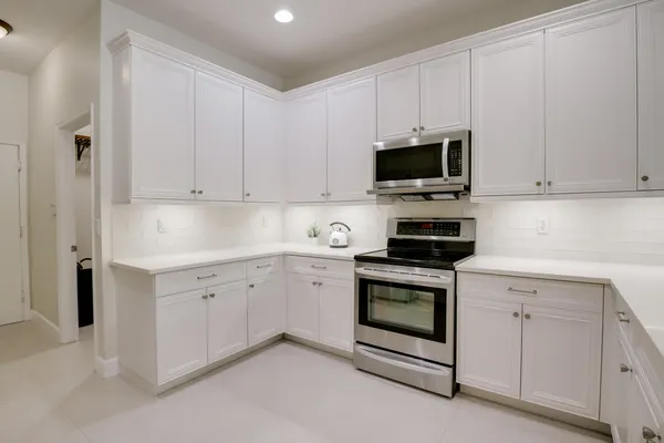 a kitchen with a sink dishwasher a stove and white cabinets