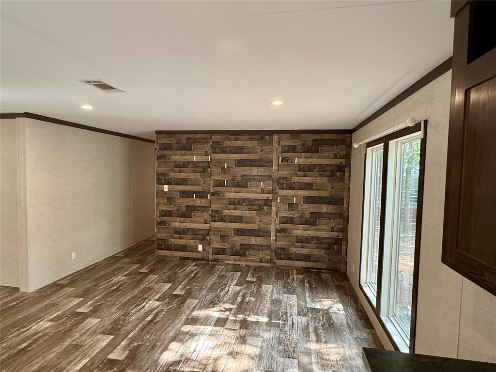 145 Adalida Lane Springtown, TX 76082 - Photo 12 of 29 Interior space featuring a decorative wood-panel accent wall, wood-finish flooring, recessed lighting, and large windows