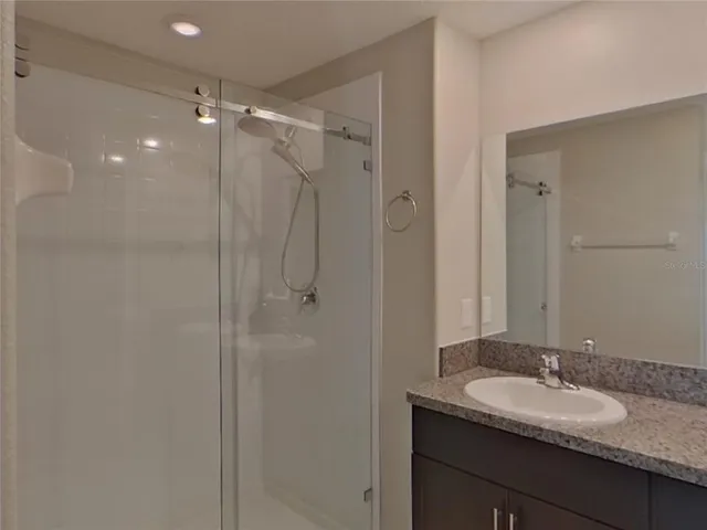 a bathroom with a granite countertop sink shower mirror and a