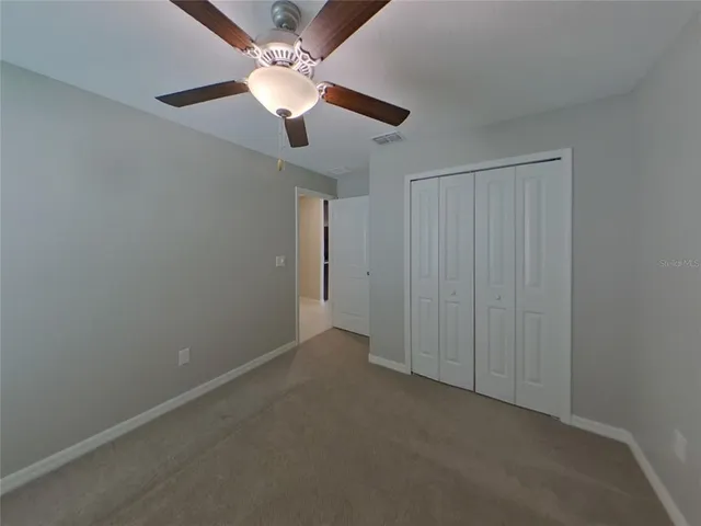 an empty room with a chandelier fan and closet area
