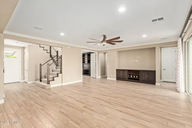 a view of an empty room with wooden floor and a ceiling fan